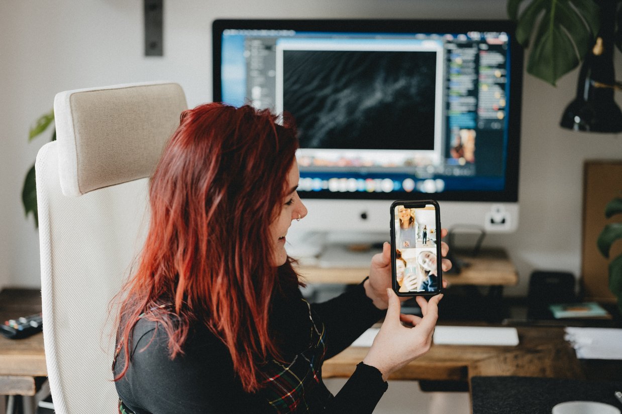 Woman showing mobile phone in a virtual meeting